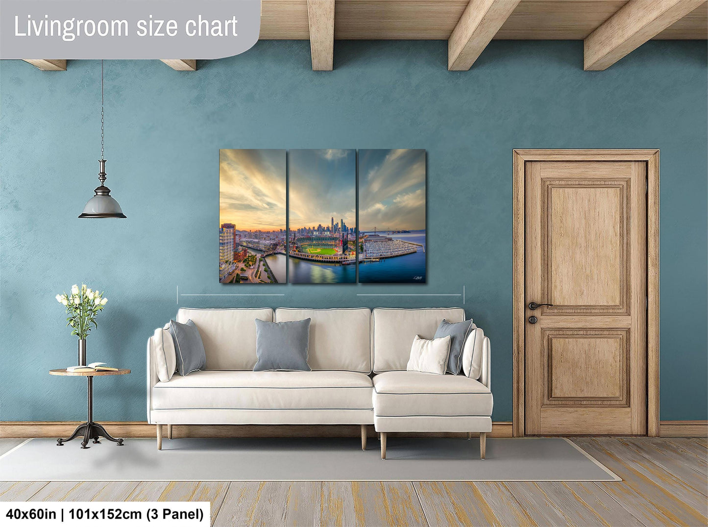 The image is a living room with a large, three-panel living room size chart on the wall, a white sofa, a wooden door, and a small table with a vase of flowers.
