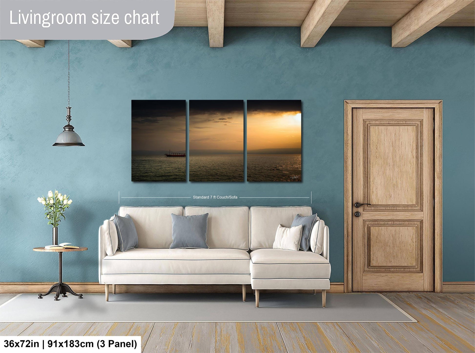The image is a living room with a white sofa, a wooden door, and a large wall art depicting a sunset over the ocean.
