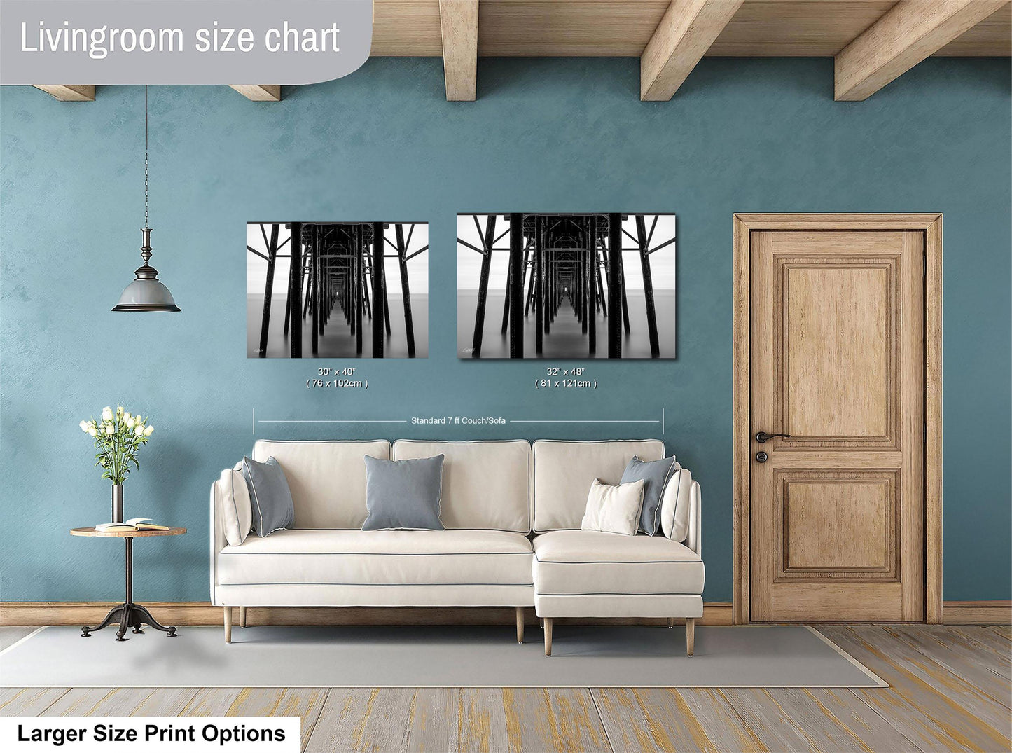 a living room with a white sofa, a wooden door, and a framed photograph of a bridge. The living room has a blue wall and a wooden ceiling.