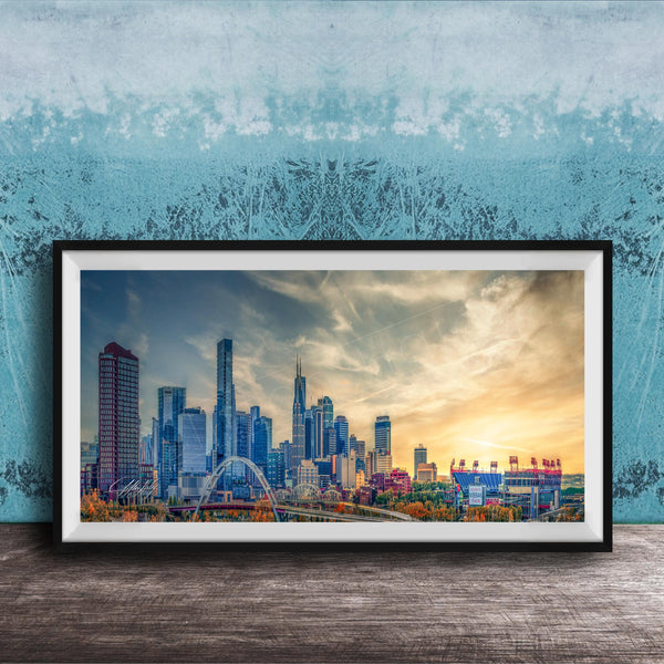 A framed photograph of a city skyline at sunset, with the city's tall buildings silhouetted against a colorful sky.