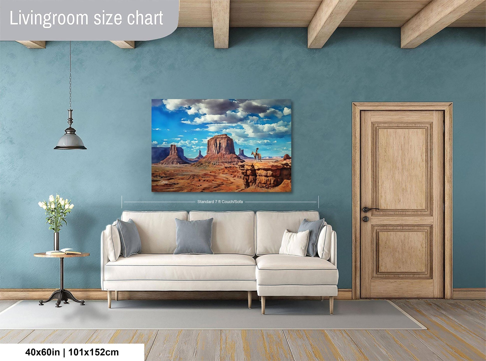 a living room with a large painting of a desert landscape hanging on the wall. The painting is framed in a white frame and measures 40 inches by 101.5 centimeters. The room has a white sofa and a wooden door, creating a cozy and modern atmosphere.