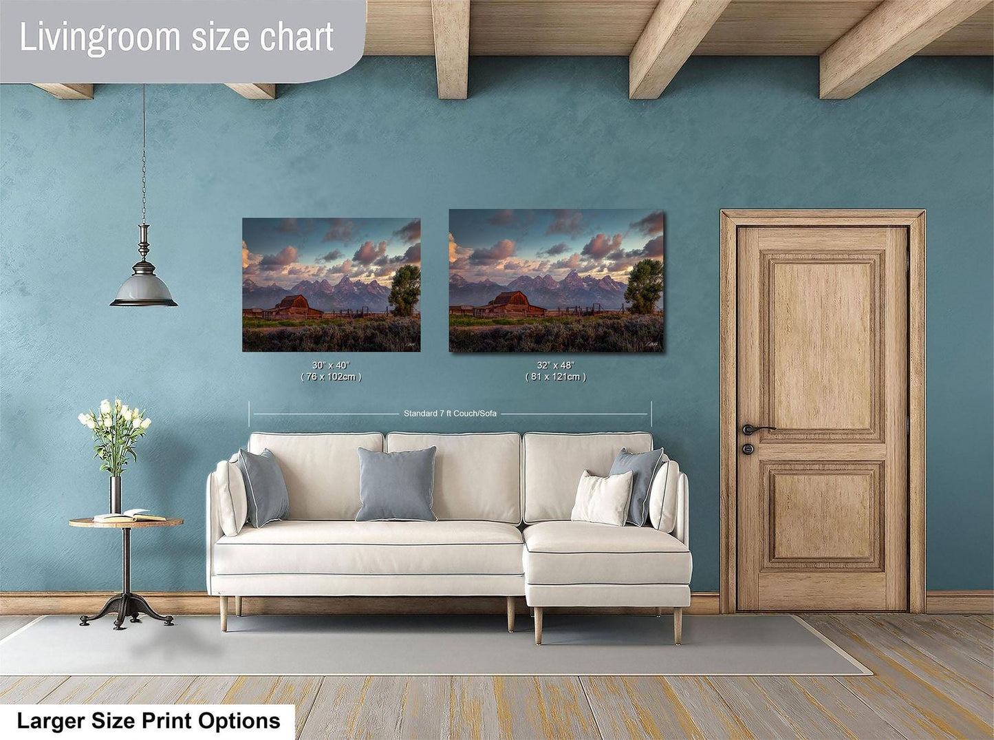 a living room with a white sofa and a wooden door. Above the sofa, there are two framed landscape paintings depicting a scenic mountain view. The paintings are of similar size, with one being larger than the other. The living room has a blue wall and a wooden ceiling, creating a cozy and inviting atmosphere.