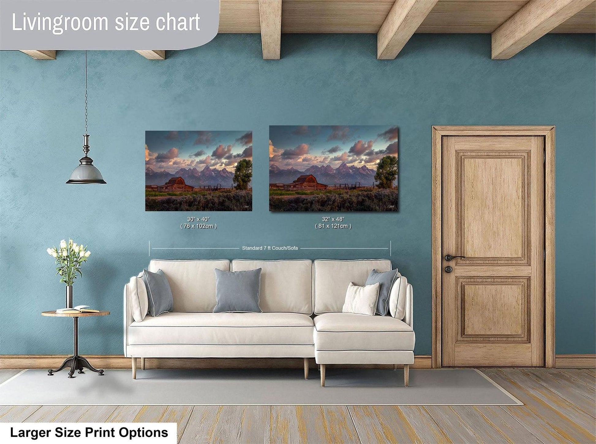 a living room with a white sofa and a wooden door. Above the sofa, there are two framed landscape paintings depicting a scenic mountain view. The paintings are of similar size, with one being larger than the other. The living room has a blue wall and a wooden ceiling, creating a cozy and inviting atmosphere.