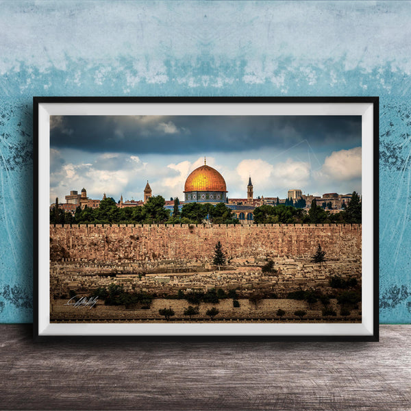 the Dome of the Rock, a significant landmark in Jerusalem, Israel. The photograph is framed and displayed on a wooden surface, showcasing the architectural beauty of the structure against a cloudy sky.