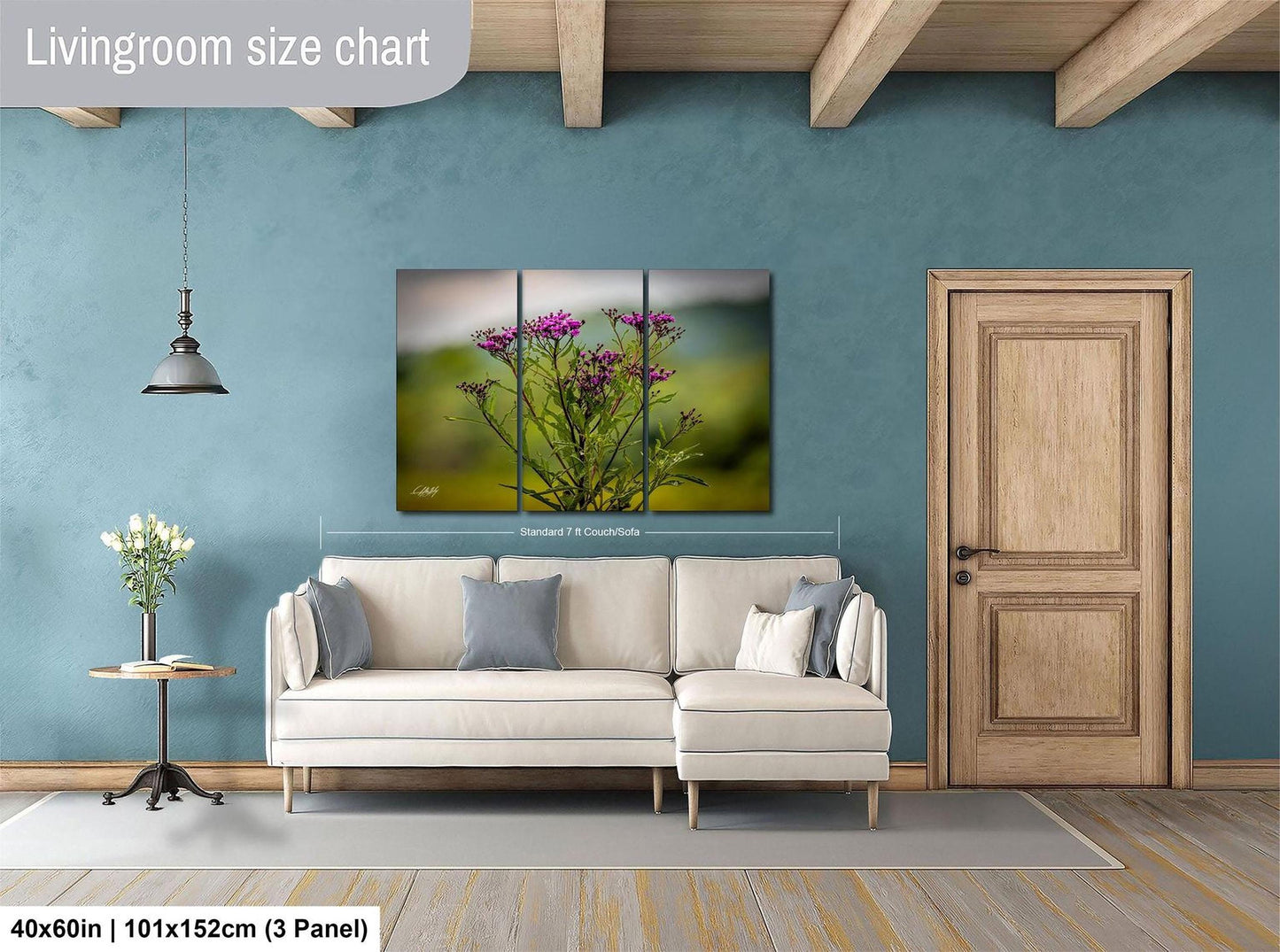 a living room with a white sofa, a wooden door, and a painting of purple flowers hanging on the wall.