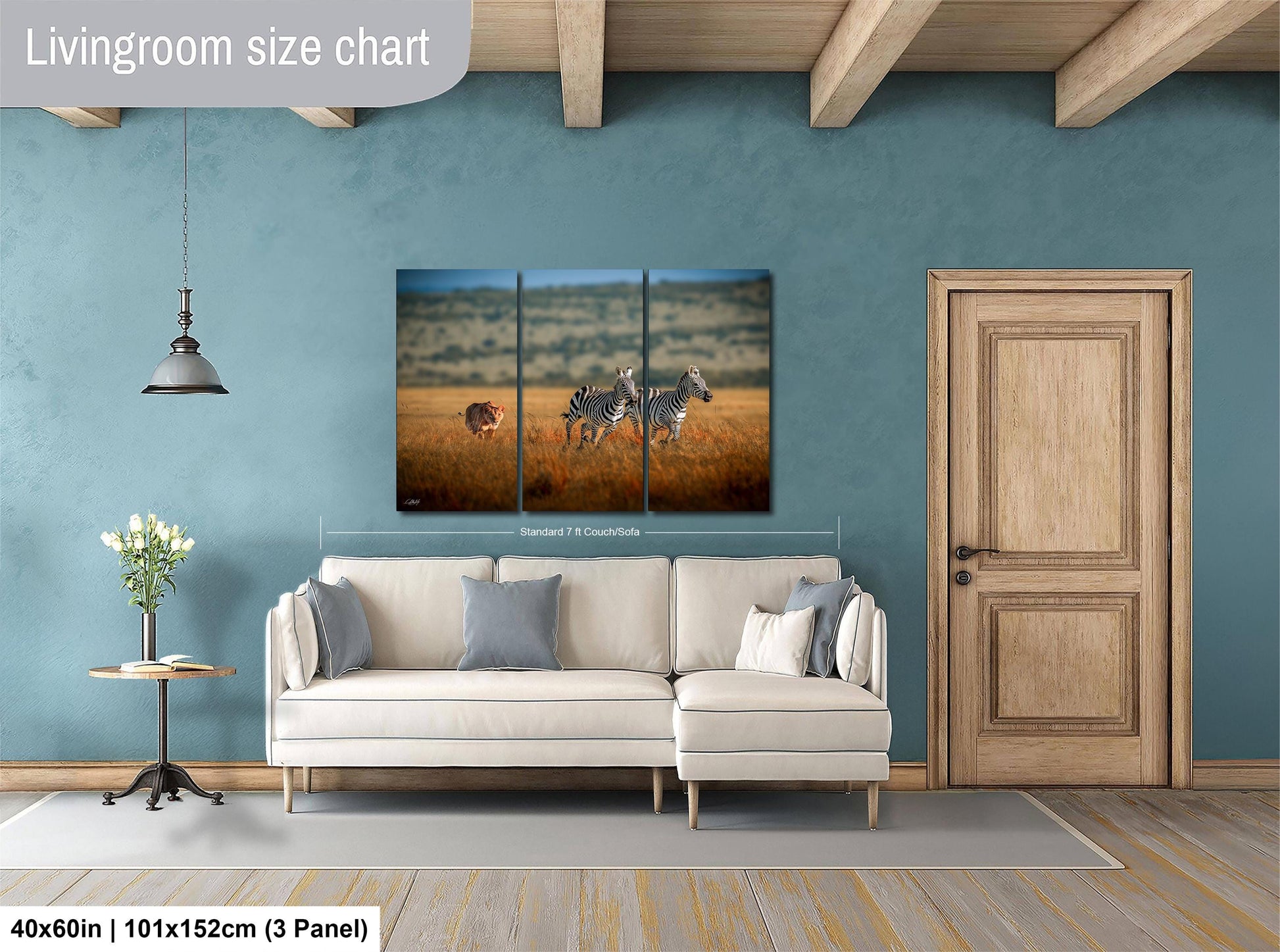 The image is a living room with a large painting of zebras in a field hanging on the wall. The painting is divided into three panels, and the living room has a white sofa and a wooden door.