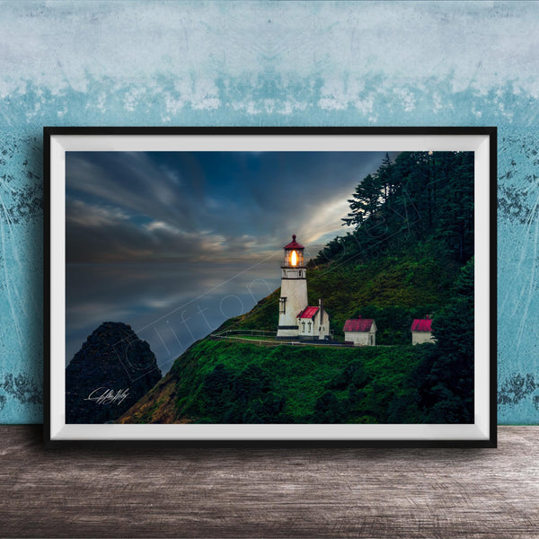 A framed photograph of a lighthouse on a cliff, with a dramatic sky and a small village in the background.