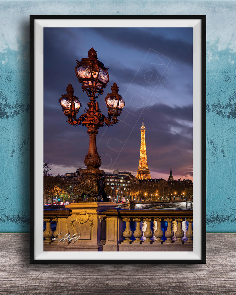 a cityscape with a lit-up lamppost and the Eiffel Tower in the background, set against a dark sky.