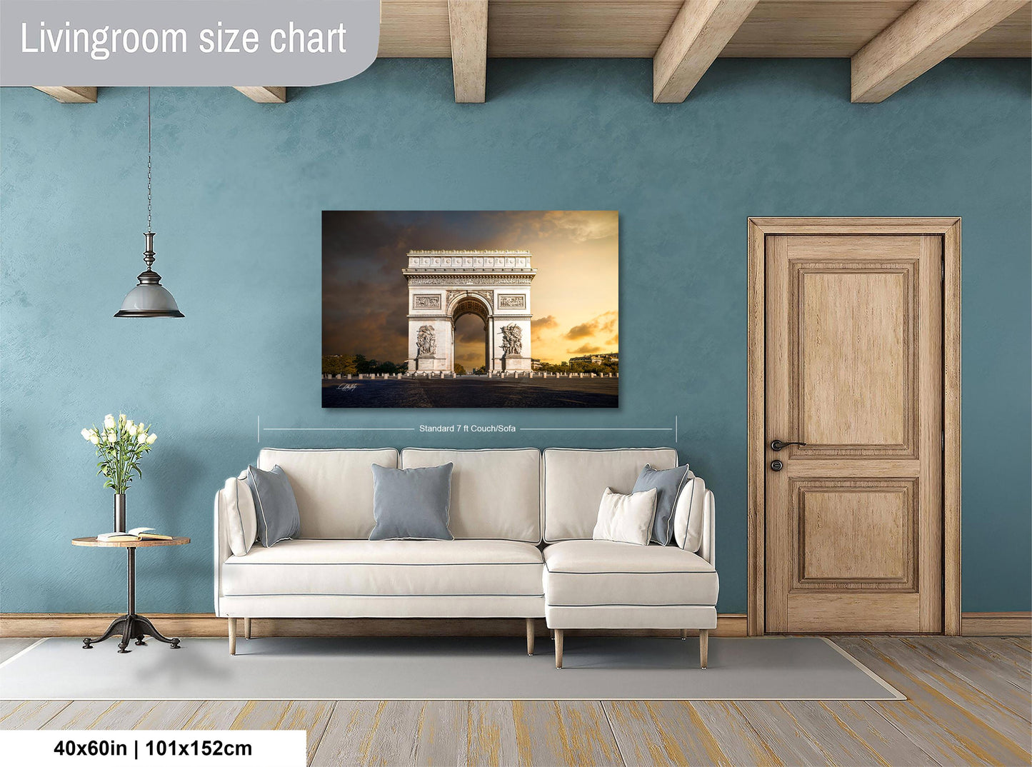 a living room with a large white sofa, a wooden door, and a painting of the Arc de Triomphe hanging on the wall.