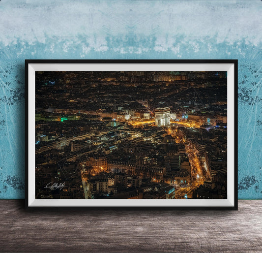 The image is a framed aerial view of a city at night, showcasing the illuminated buildings and streets below.