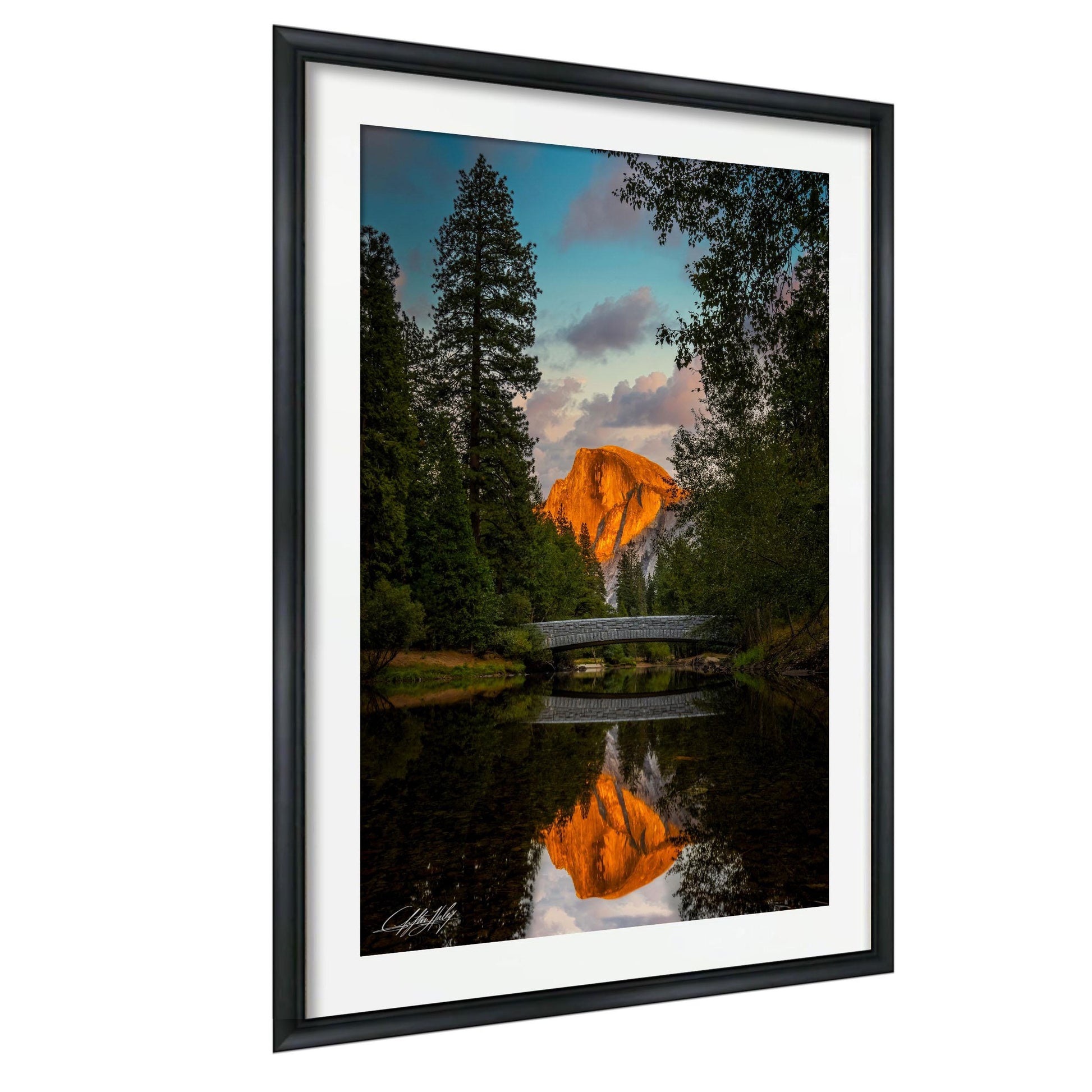 a serene landscape with a mountain in the background, a bridge in the foreground, and trees surrounding the area. The sky is filled with clouds, creating a beautiful reflection on the water below.