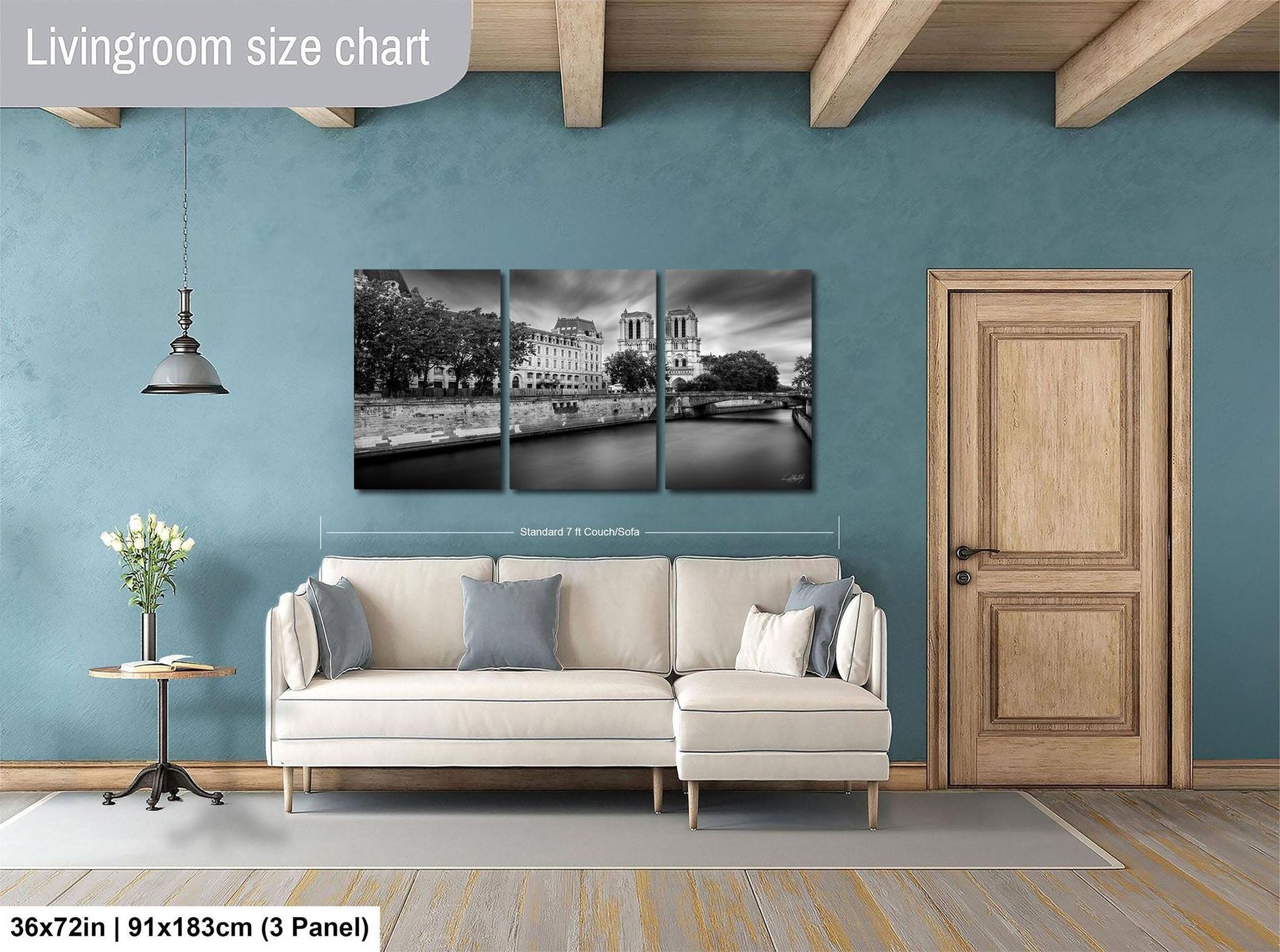 The image is a living room with a large wall art piece depicting a cityscape. The art piece is divided into three panels, each showing different parts of the city. The living room has a white sofa and a wooden door, and the floor is covered with a gray rug.