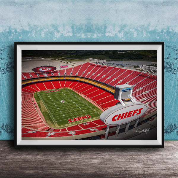 The image is a framed photograph of a football stadium, specifically the Kansas City Chiefs stadium, with the team's logo prominently displayed on the field.