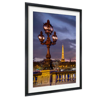 a large ornate street lamp with multiple lights, set against the backdrop of the Eiffel Tower and the city of Paris at night.