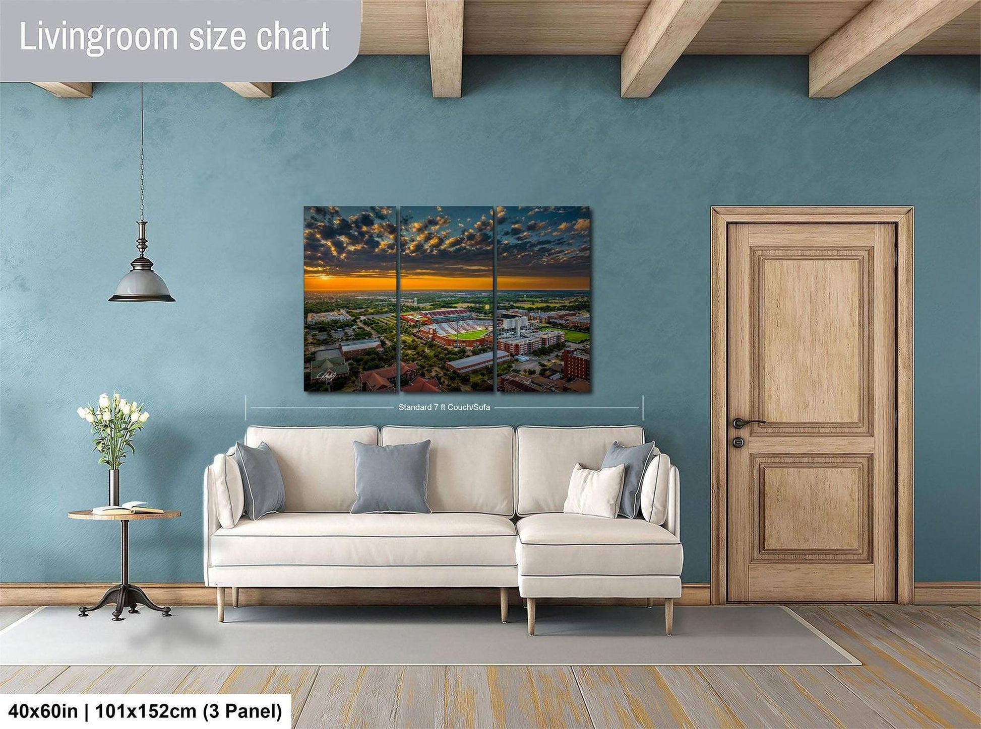 The image is a living room with a large white sofa, a wooden door, and a painting of a cityscape hanging on the wall.