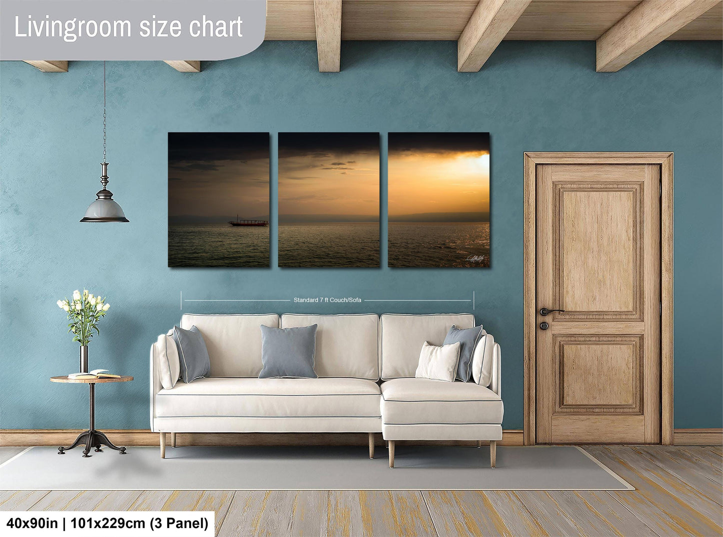 The image is a living room with a white sofa and a wooden door. Above the sofa, there is a triptych of landscape paintings depicting a sunset over the ocean. The paintings are framed and hung on the wall.
