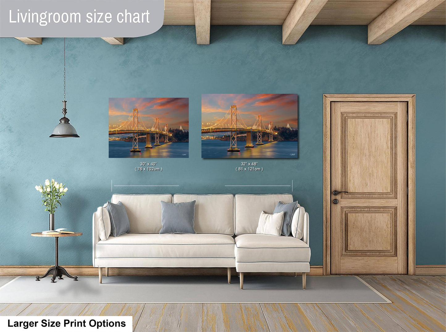 a living room with a white sofa and a wooden door. Above the sofa, there are two framed pictures of a bridge at sunset, with the size of the pictures being 30x60 inches and 31x42 inches.