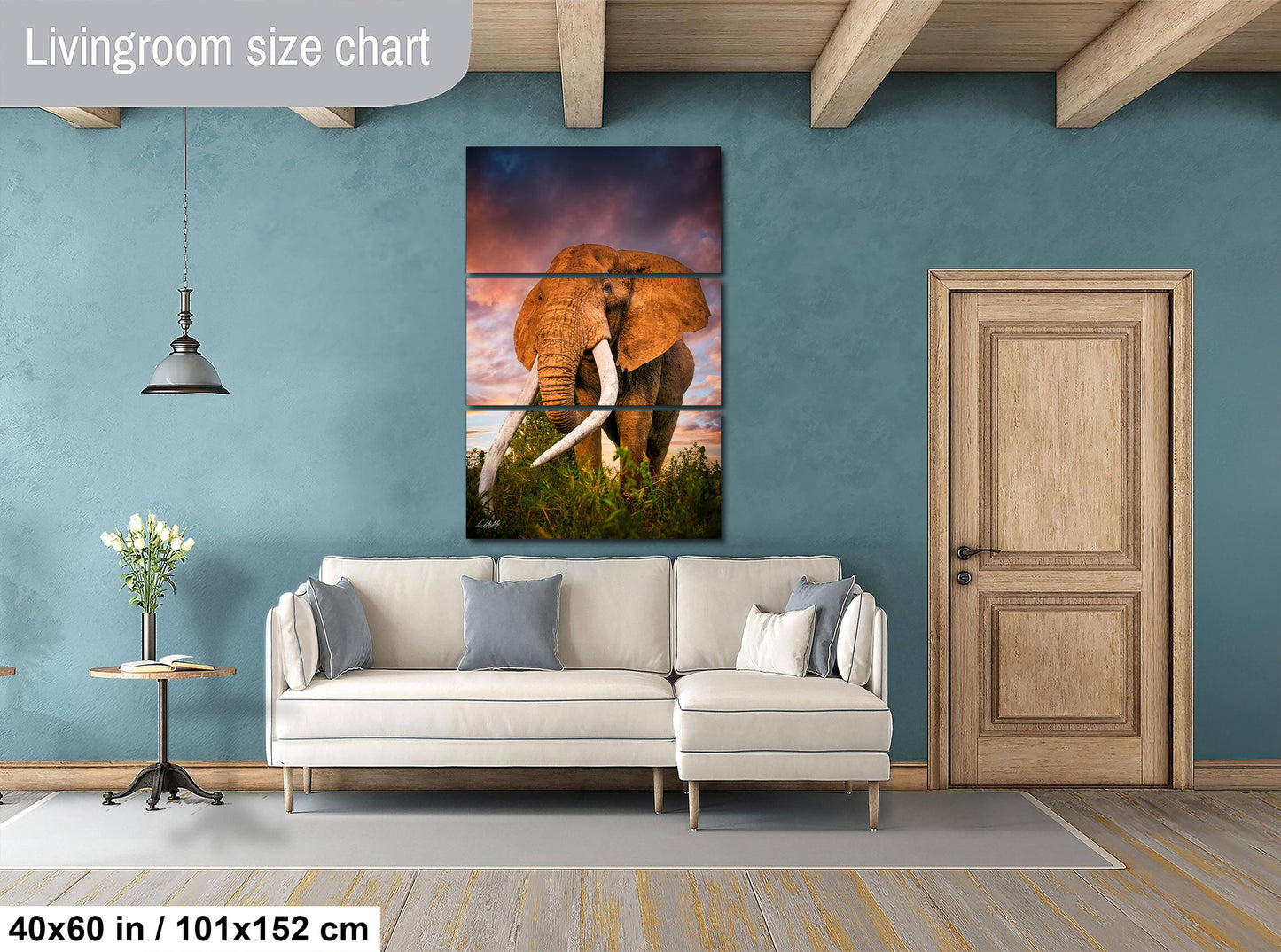 The image is a living room with a large painting of an elephant on the wall. The painting is divided into three sections, depicting the elephant in different stages of its appearance. The room has a white sofa, a wooden door, and a small table with a vase of flowers. The wall is painted in a light blue color, and the floor is covered with a gray rug. The image is labeled with the dimensions "4060 in |101152 cm" and the phrase "Livingroom size chart".