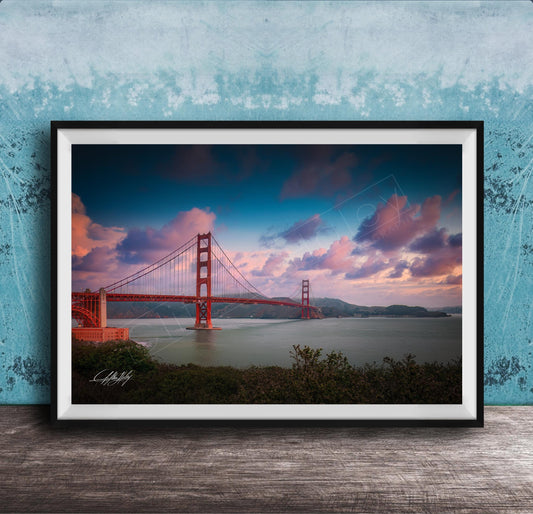 A framed photograph of the Golden Gate Bridge at sunset, with the bridge's distinctive red towers and suspension cables silhouetted against a colorful sky.