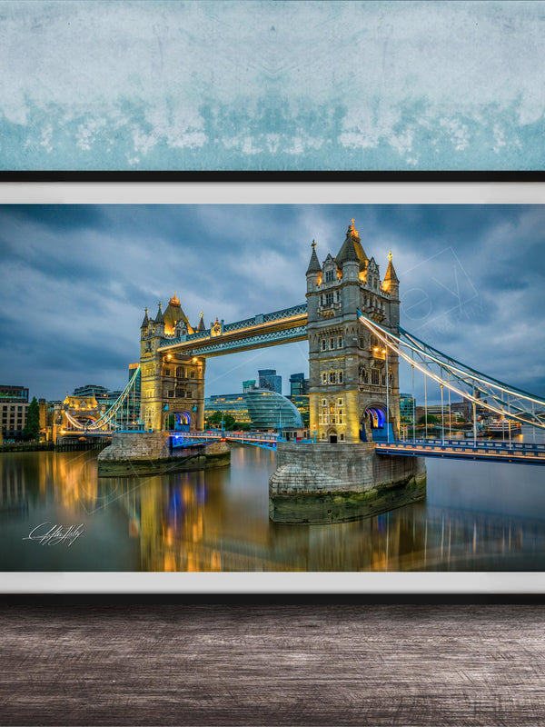 A framed photograph of the iconic Tower Bridge in London, England, illuminated at night against a cloudy sky.