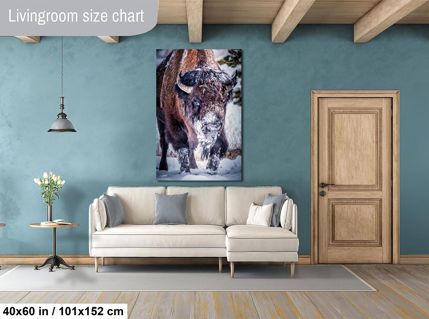 a living room with a large painting of a bison on the wall, a white sofa, a wooden door, and a small table with a vase of flowers.