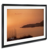 a serene sunset over a body of water, with a small island visible in the distance.
