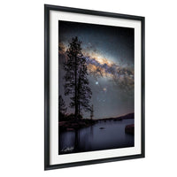 a serene night scene with a starry sky and a calm lake, framed by silhouetted trees.