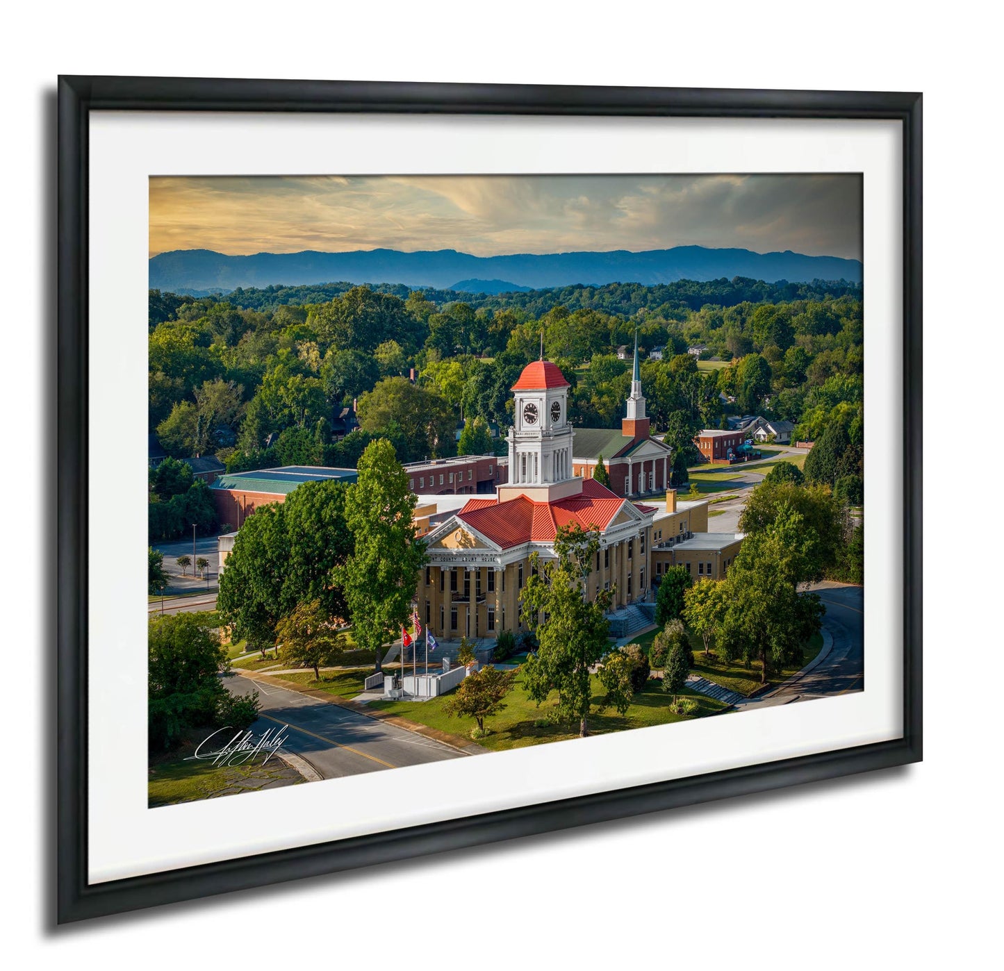 a large, ornate building with a red roof and a clock tower, surrounded by lush greenery and mountains in the background.