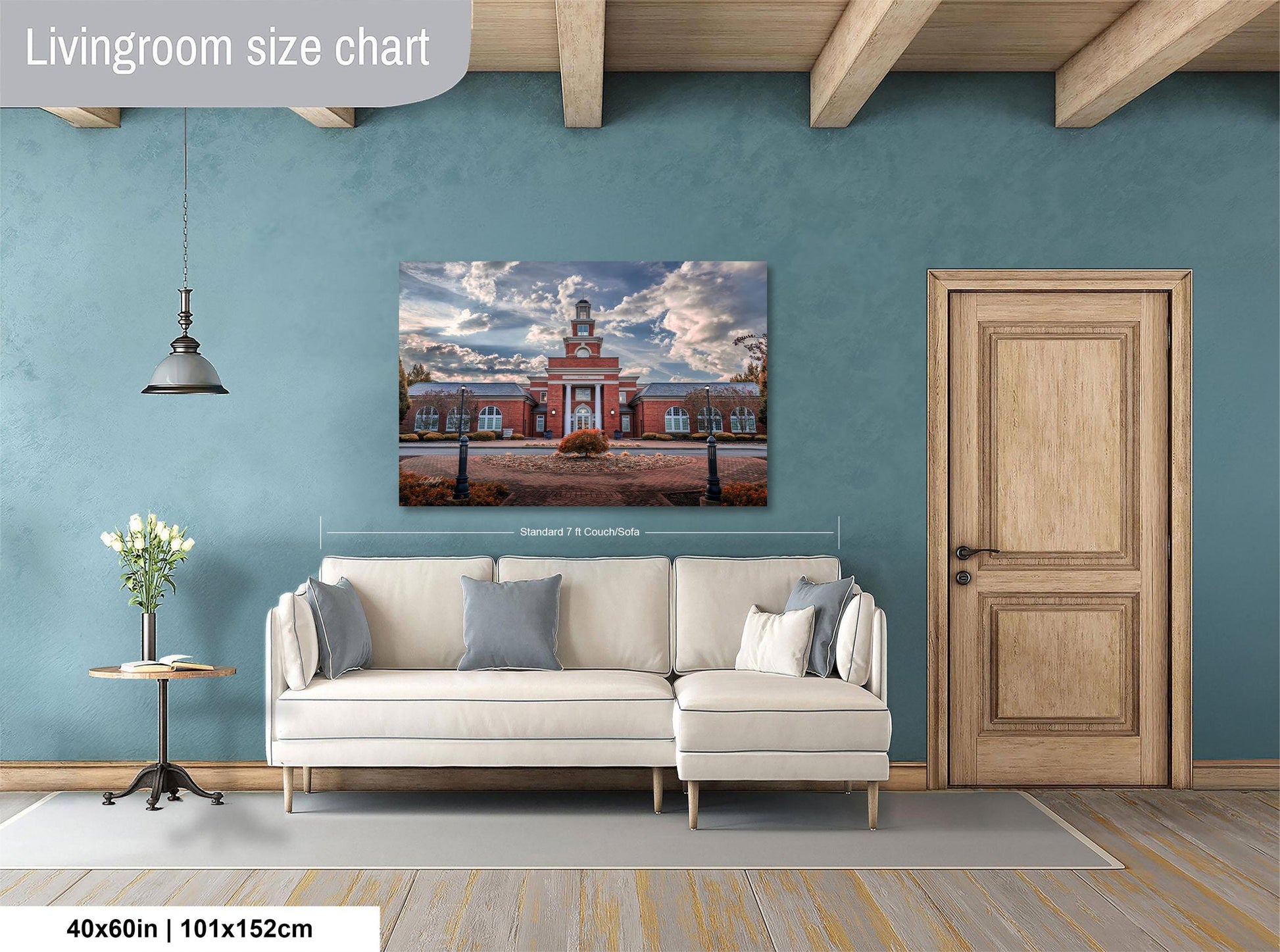 a living room with a large painting of a building on the wall, a white sofa, a wooden door, and a small table with a vase of flowers.