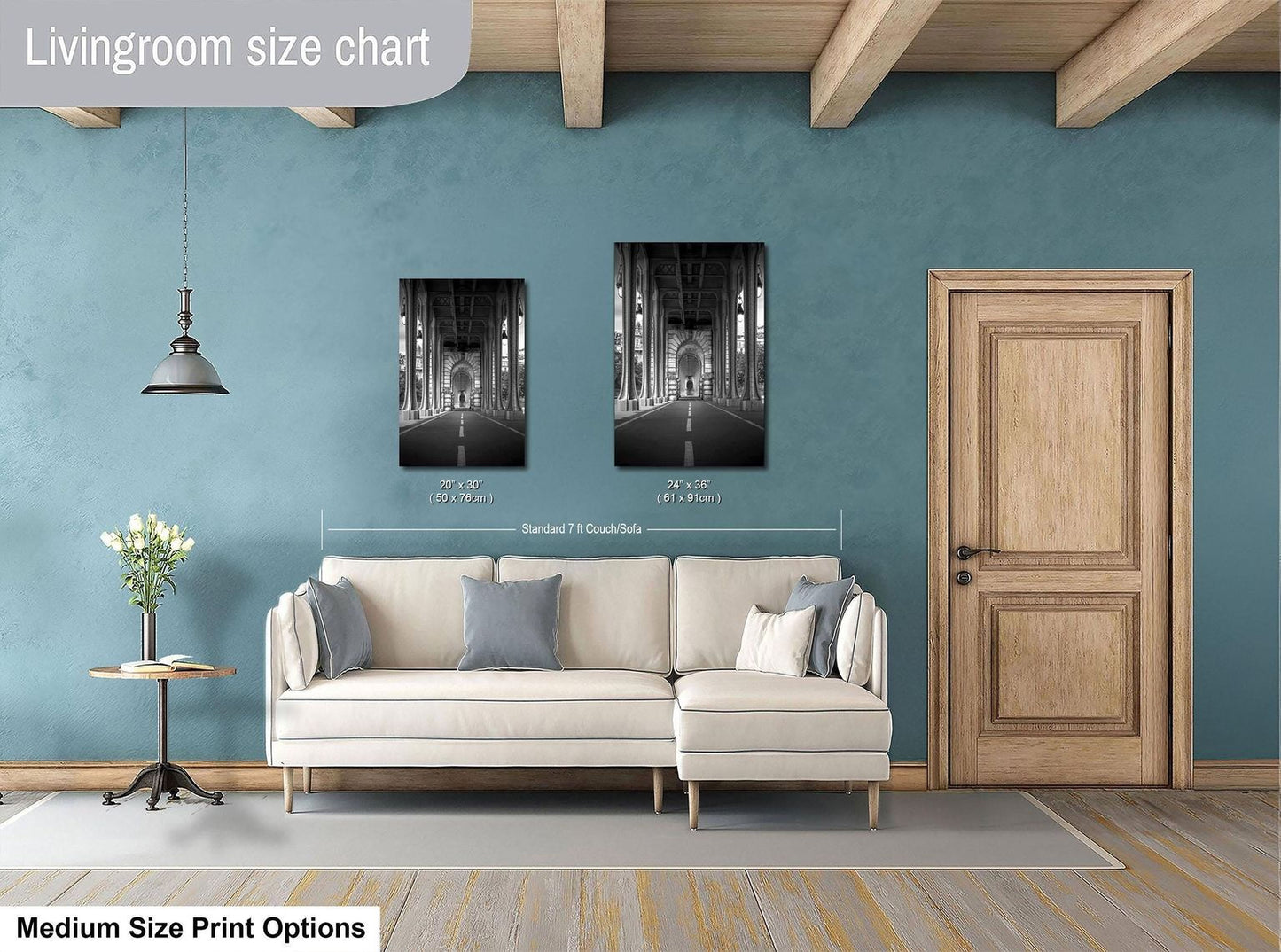 a living room with a white sofa, a wooden door, and a framed black and white photograph of a cathedral. The sofa is positioned in front of the door, and the photograph is hung above it. The living room appears to be well-lit and decorated with a vase of flowers on a table.