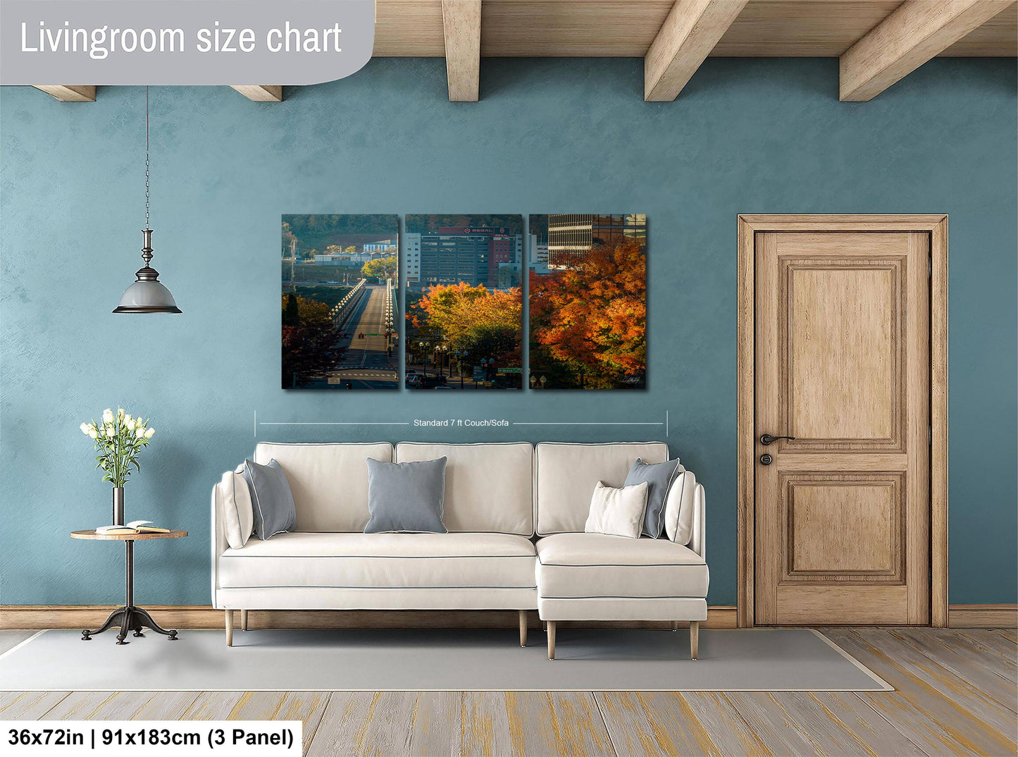 The image is a living room with a large white sofa, a wooden door, and a hanging light fixture. Above the sofa, there is a large living room size chart that provides dimensions for the artwork displayed on the wall.