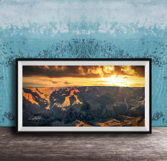 A framed photograph of a breathtaking landscape, depicting a dramatic sunset over a rugged mountain range.