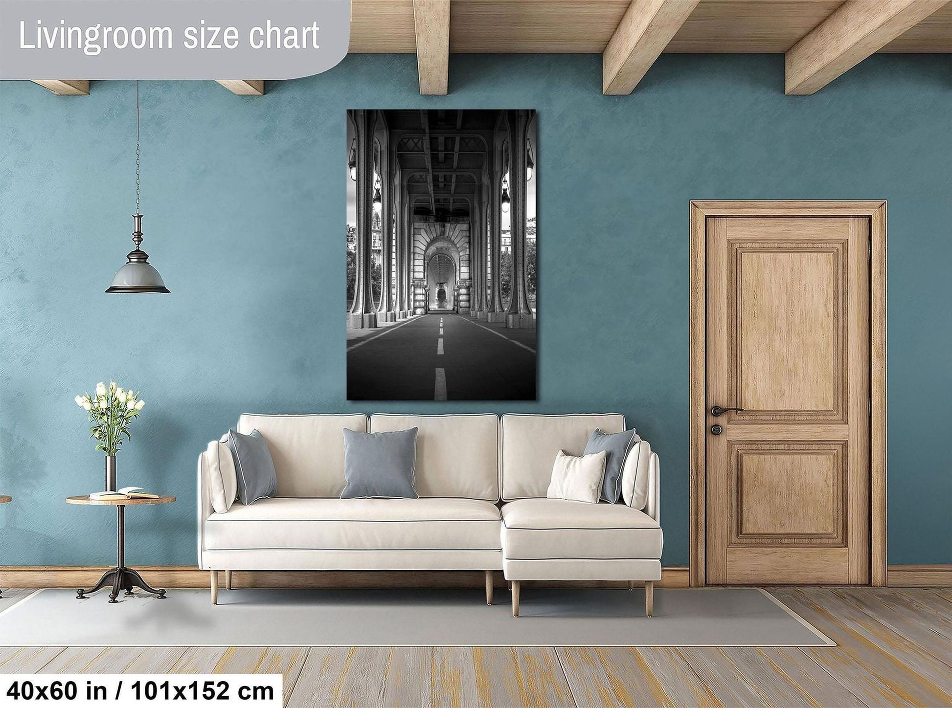 a living room with a large white sofa, a wooden door, and a black and white photograph of a hallway with columns on the wall.
