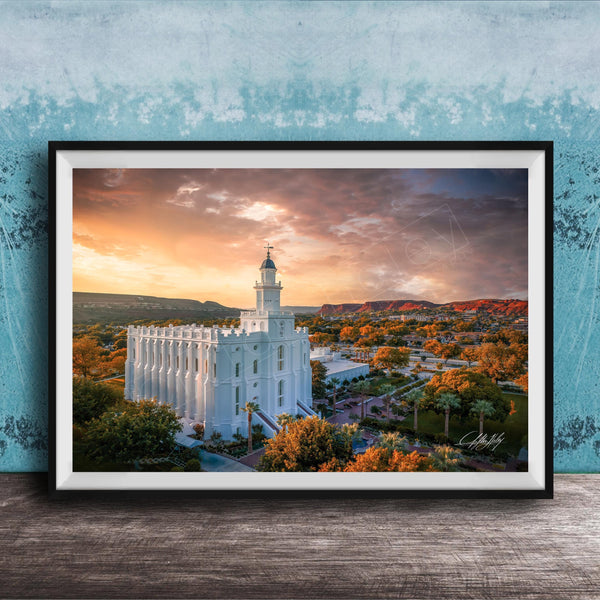 A framed photograph of a white temple with a tower, set against a colorful sunset sky with clouds and mountains in the background.