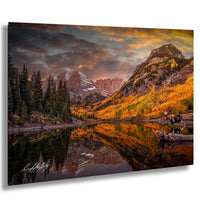 a serene mountain landscape with a lake reflecting the vibrant colors of the autumn foliage. The mountains are adorned with a mix of green and orange trees, creating a picturesque scene. The sky above is filled with clouds, adding to the dramatic atmosphere of the landscape. In the foreground, there is a horse standing near the lake, adding a touch of life to the otherwise tranquil setting.