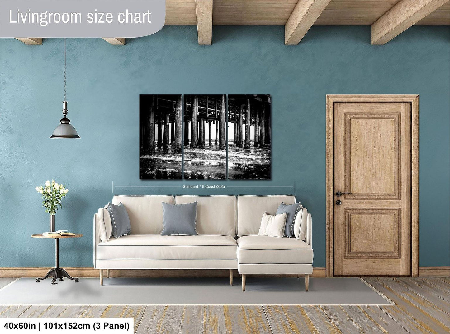 a living room with a large white sofa, a wooden door, and a black and white photograph of a bridge hanging on the wall.