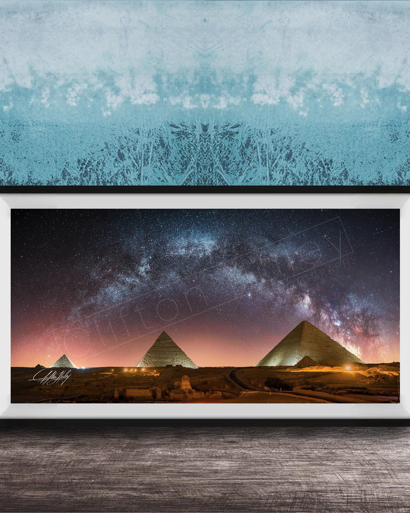 a framed photograph of the pyramids of Giza at night, with the stars visible in the sky above the ancient structures.