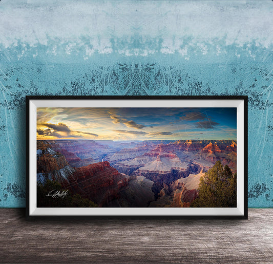 A framed photograph of the Grand Canyon, showcasing the vast and breathtaking landscape with its dramatic rock formations and vibrant colors at sunset.
