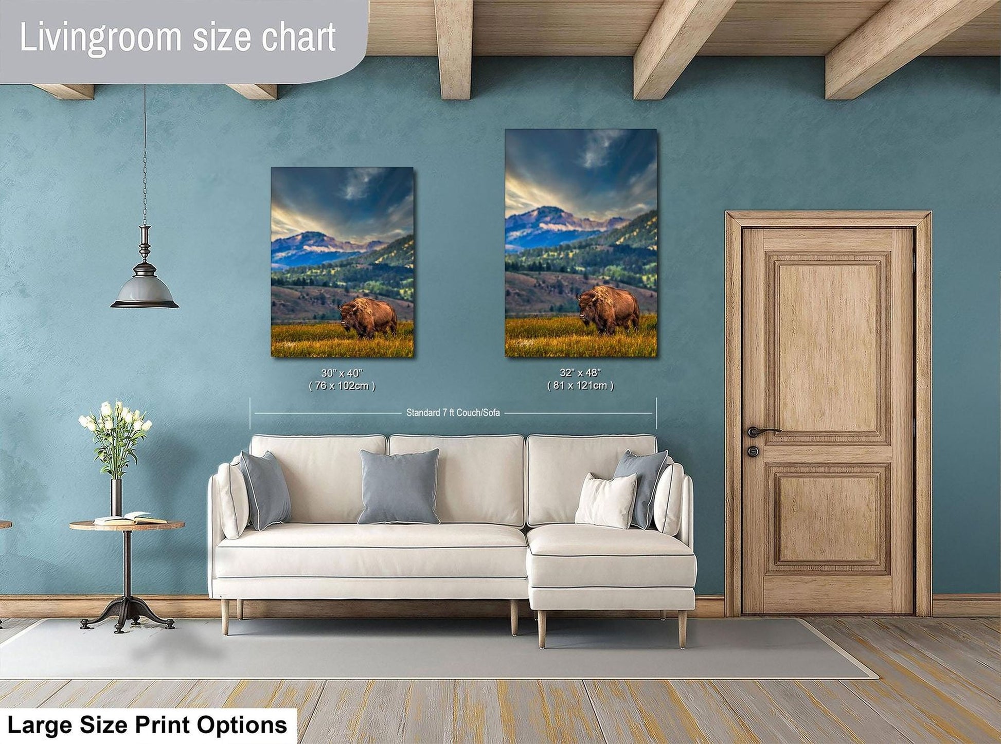 a living room with a white sofa and a wooden door. There are two framed landscape paintings hanging on the wall, depicting a scenic mountain landscape. The paintings are of similar size, and the wall is painted in a light blue color.