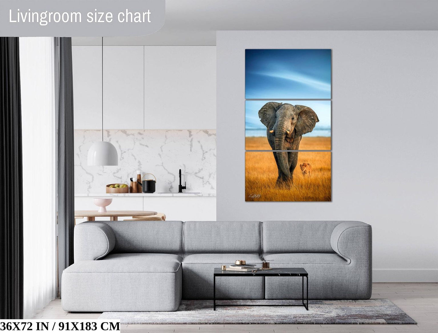 The image is a living room with a gray sofa, a coffee table, and a large painting of an elephant in a field. The painting is a triptych, with the top and bottom panels depicting the elephant and the background, and the middle panel showing the elephant in the foreground. The room has a modern and minimalist design, with white walls and a gray sofa.