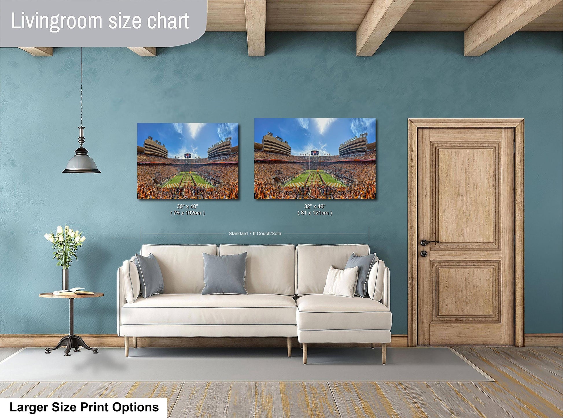 a living room with a white sofa and a wooden door. Above the sofa, there are two framed pictures of a stadium, likely representing a sports event. The living room has a blue wall and a wooden ceiling.