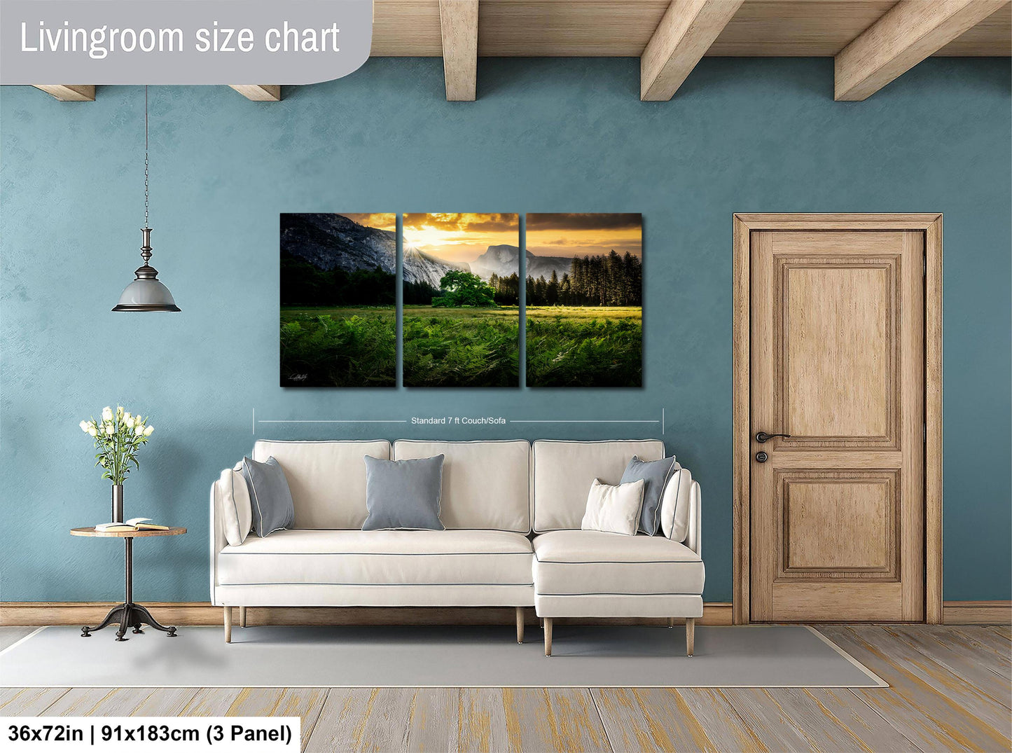 The image is a living room with a large, three-panel landscape painting hanging on the wall. The painting depicts a serene mountain landscape with a sunset. The room has a white sofa and a wooden door, creating a cozy and inviting atmosphere.