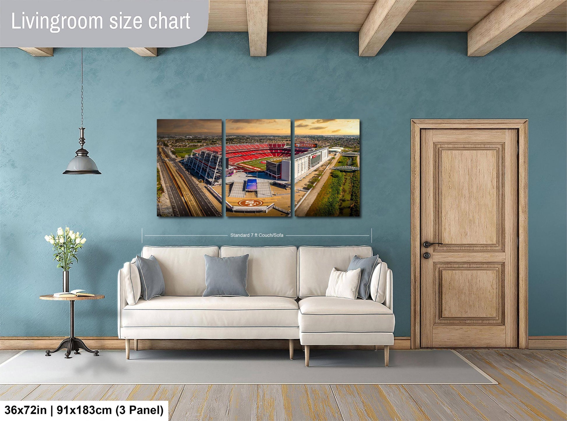 The image is a living room with a large white sofa, a wooden door, and a wall-mounted three-piece wall art depicting a stadium.