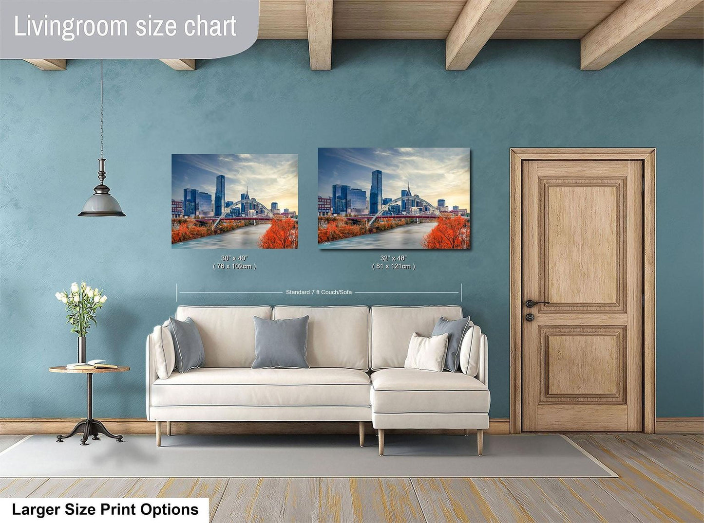 a living room with a white sofa and a wooden door. Above the sofa, there are two framed pictures of a city skyline, with one picture being larger than the other. The living room has a blue wall and a wooden ceiling.