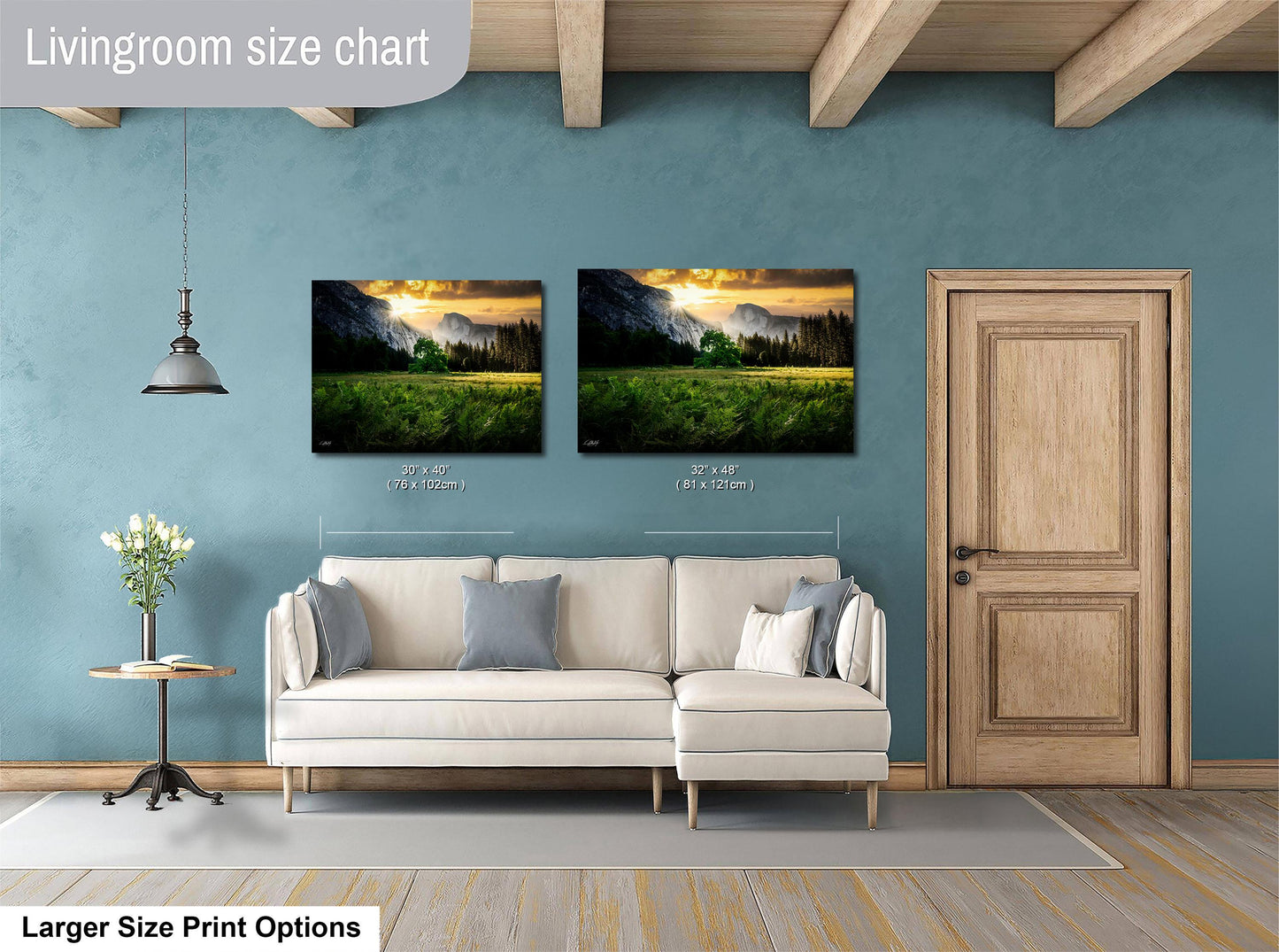 a living room with a white sofa and a wooden door. Above the sofa, there are two framed landscape paintings depicting a serene mountain scene. The paintings are of similar size, with one being larger than the other. The living room has a blue wall and a wooden ceiling, creating a cozy and inviting atmosphere.