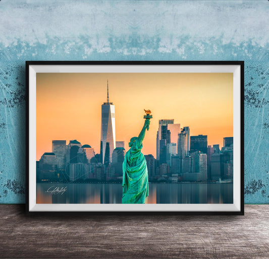 A framed photograph of the Statue of Liberty in New York City, with the city skyline in the background.