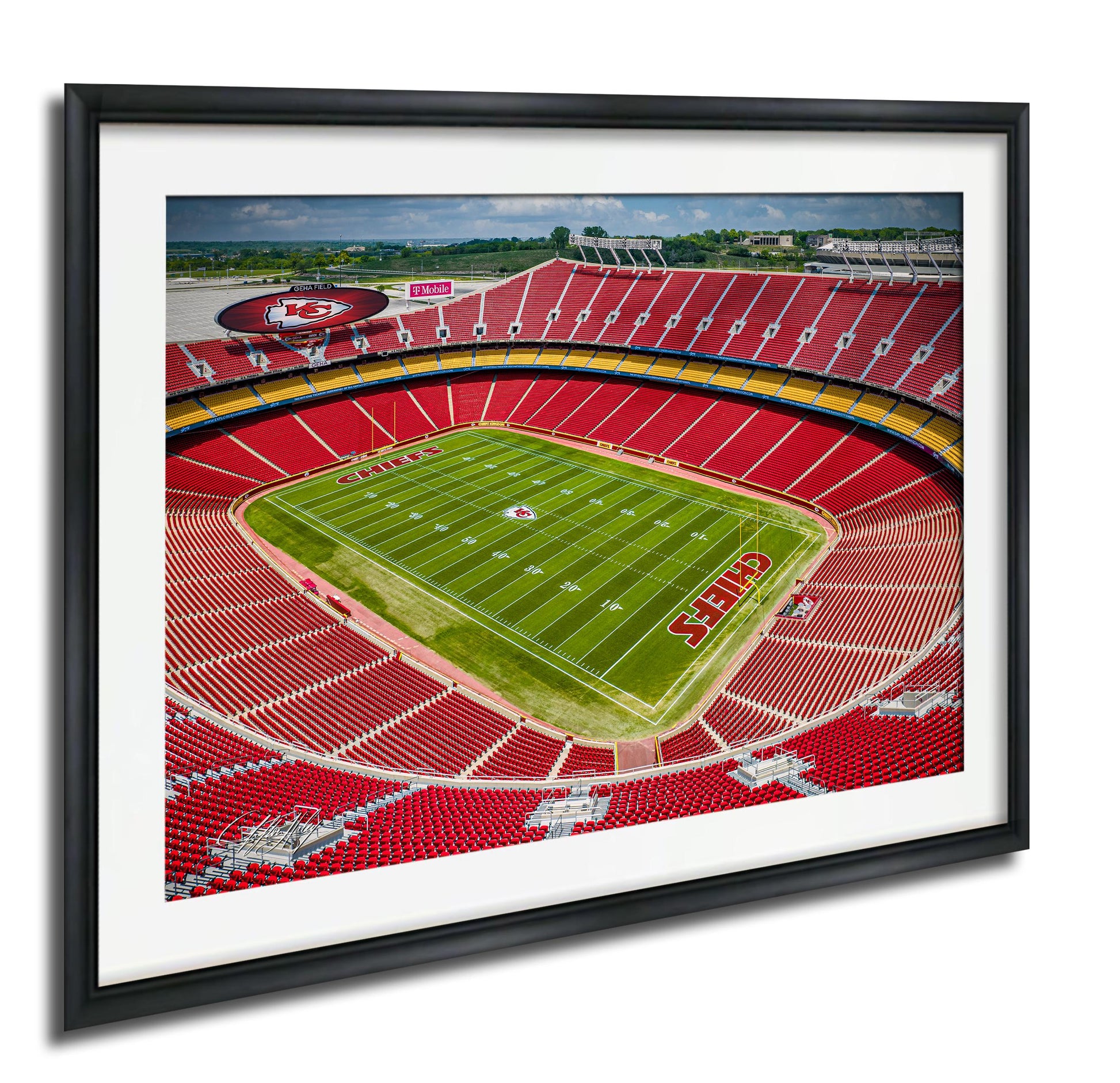 a framed aerial view of a football stadium with a green field and red seating.