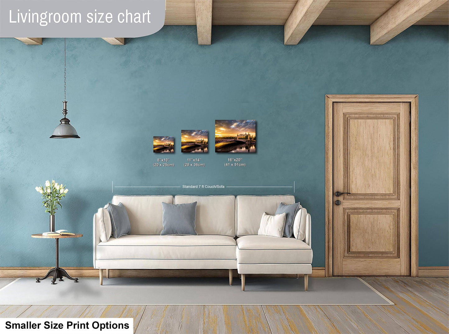 a living room with a white sofa, a wooden door, and a hanging light fixture. There are three framed pictures of landscapes displayed on the wall above the sofa.