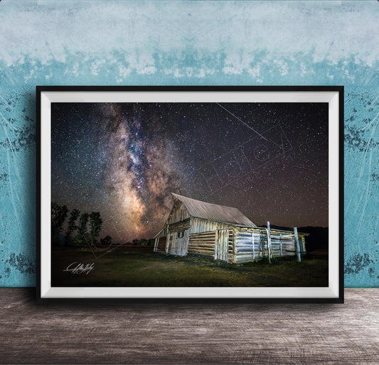 A framed photograph depicting a rustic wooden barn under a starry night sky, with the Milky Way galaxy visible in the background.