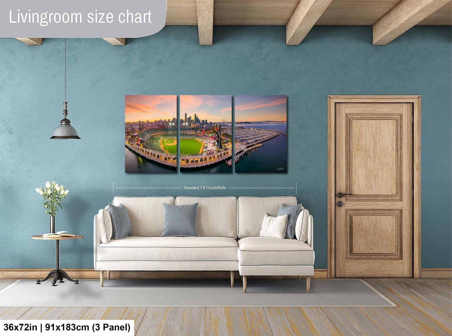 The image is a living room with a large wall art depicting a city skyline at sunset. The wall art is a collage of three panels, with the largest panel spanning approximately 36 square inches. The smaller panels are also visible, but their exact size cannot be determined from the image.